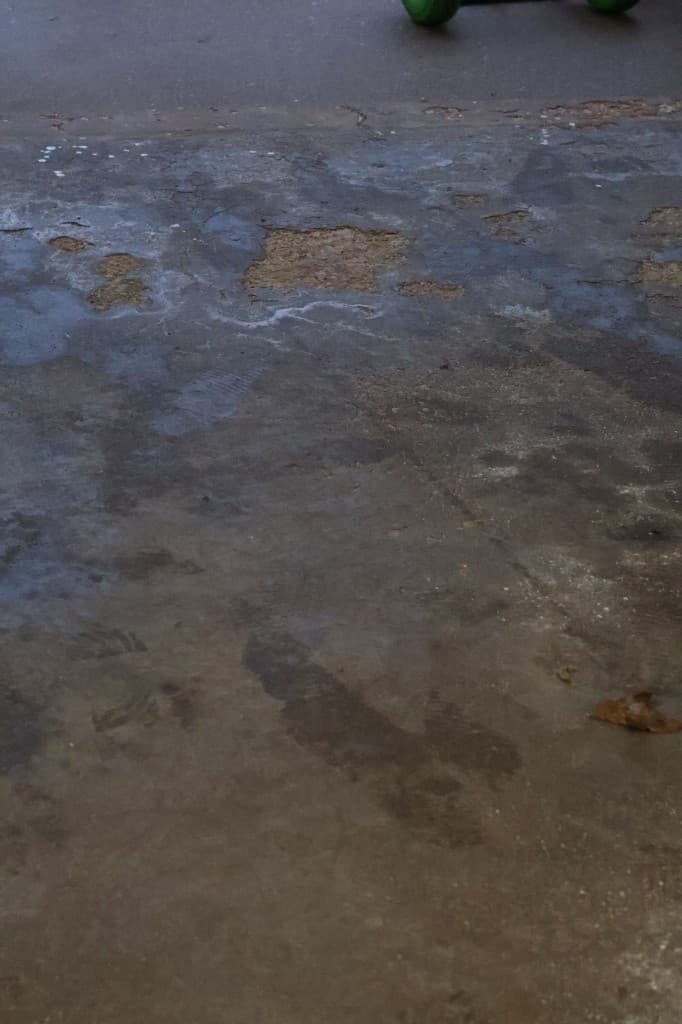 Before coating: chipped and worn garage concrete.