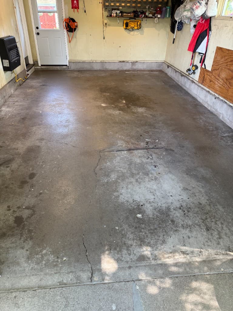 Before coating: cracked and stained concrete garage floor.