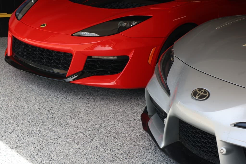 Finished grey flake garage floor coating with a red Lotus and silver Toyota Supra parked on the surface.