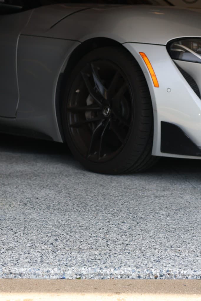 Close-up of a finished grey and blue flake garage floor with a sports car parked on the coating.