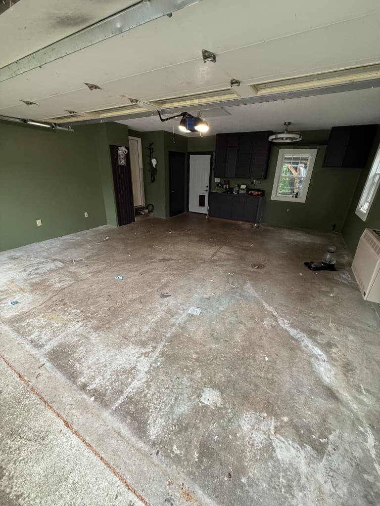 Plain concrete garage floor before coating, olive green walls.